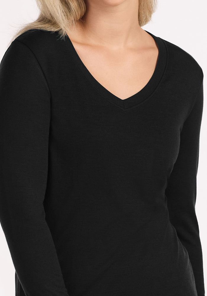 A person with long blonde hair wears the Woolx Lily V Neck Lounge Top in black, shown from shoulders to waist against a plain background—ideal for travel sleepwear or managing night sweats.