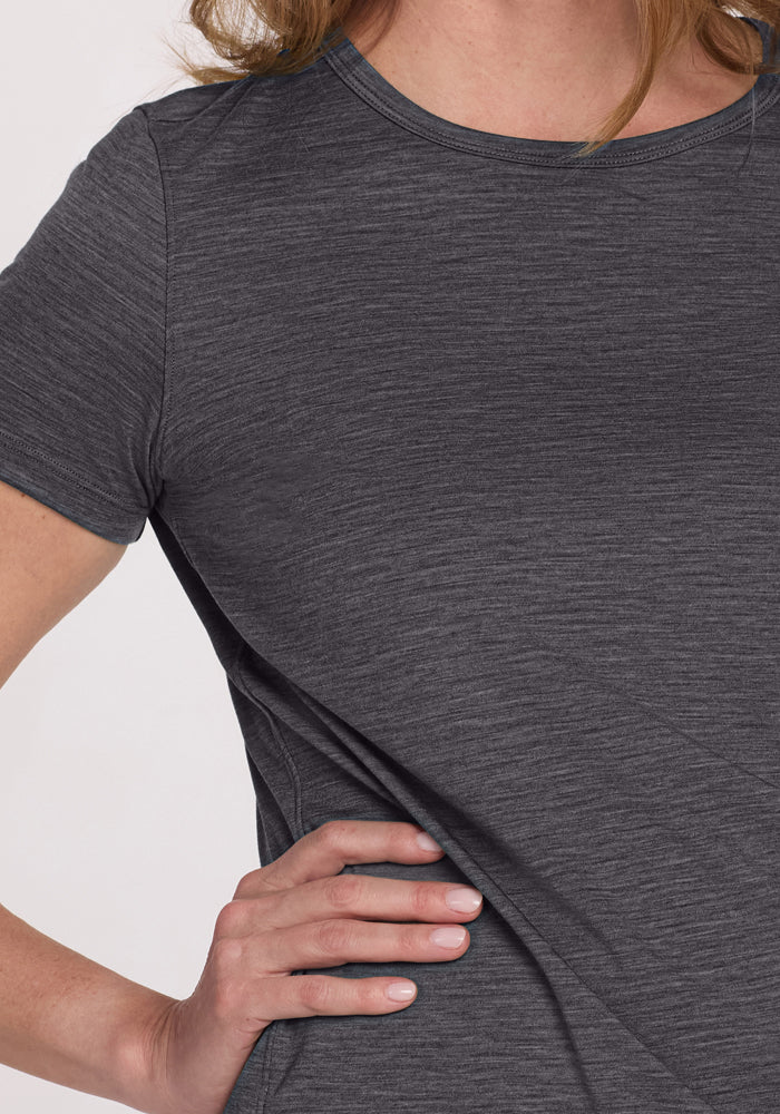 A person wearing the Woolx Liza Crew Neck Tee in Cinder Melange stands with one hand on their hip; only their torso and part of one arm are visible.