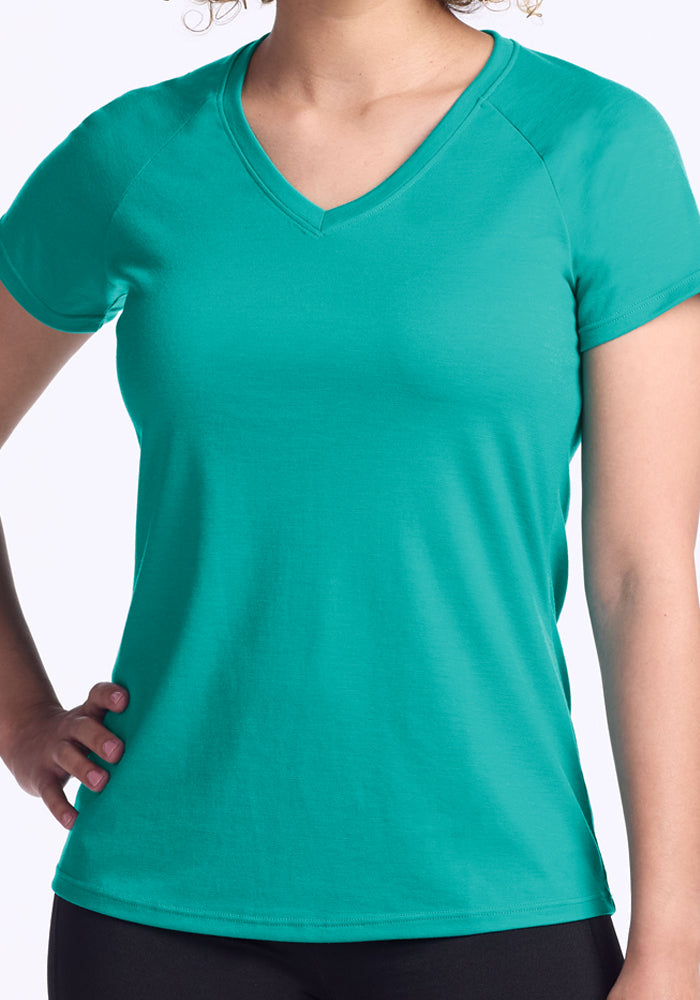 A person wearing the Woolx Mia V Neck - Cool Jade women’s tee and black pants stands with one hand on their hip against a white background.