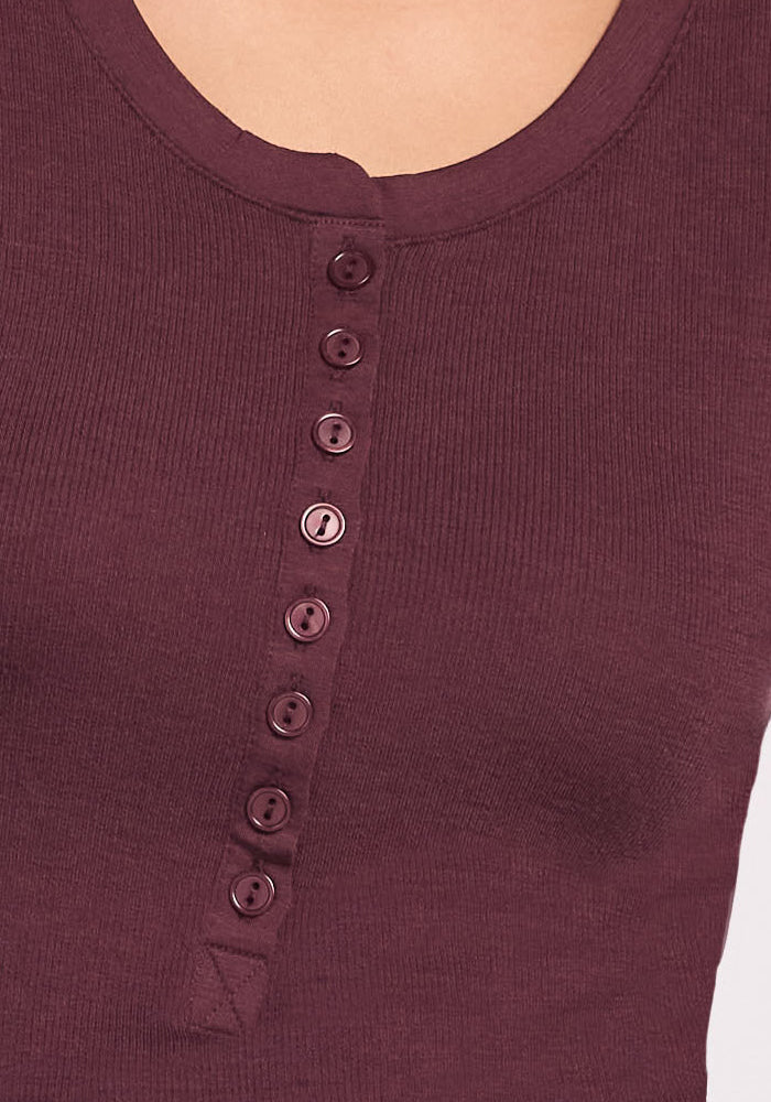 Close-up of the Woolx Reese Ribbed Henley in Chocolate Fig, showing its scoop neckline and vertical row of matching buttons. Only the upper chest and part of the neck are visible.