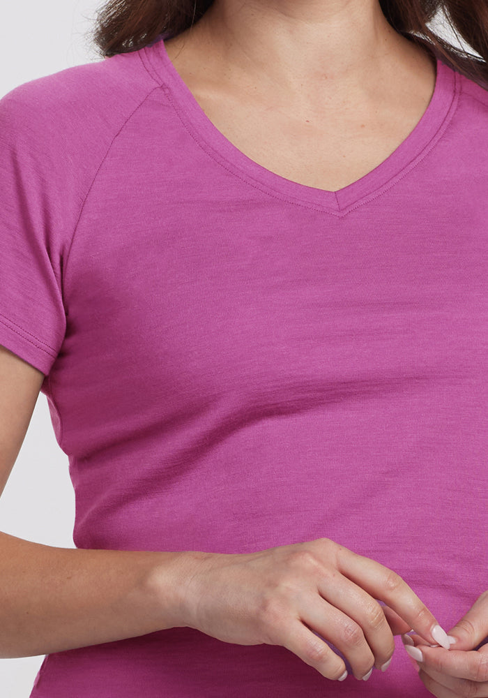 A person wearing the Woolx Mia V Neck in Purple Wine, a short-sleeved Merino wool shirt, is pictured from shoulders to waist with hands gently clasped in front.