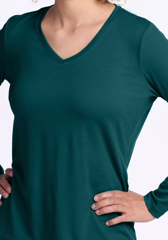 A person wearing the Woolx Millie Long Sleeve in Riverbank Green stands with hands on hips against a light background. Their face is not visible.