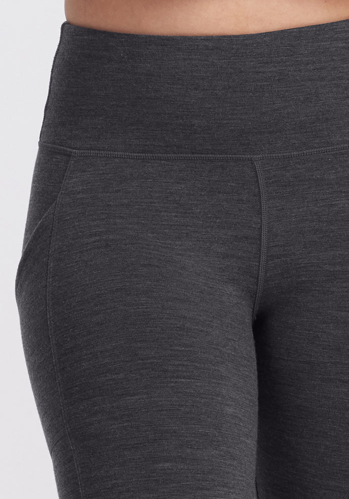 Close-up of a person wearing Woolx Piper Pocket Leggings in Cinder Melange, highlighting the high-waisted waistband and upper thigh area. The smooth, stretchy, moisture-wicking fabric ensures comfort and a flattering fit.