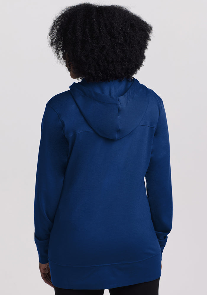 A person with curly hair is shown from the back, wearing the Woolx Ryann Hoodie in Estate Blue—an ideal travel essential—against a plain light background.