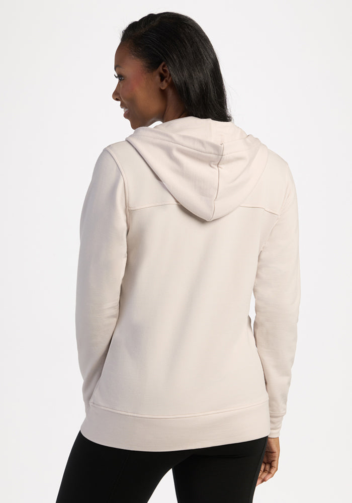 Person in Woolx Darby Zip Up Hoodie in Ecru, facing away with hands at sides against a plain background.