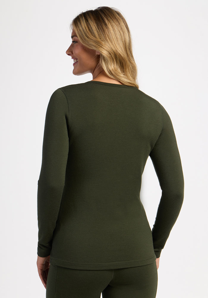 Woman in Woolx Elsa Long Sleeve - Duffel Bag, smiling and enjoying cozy winter comfort, facing away.
