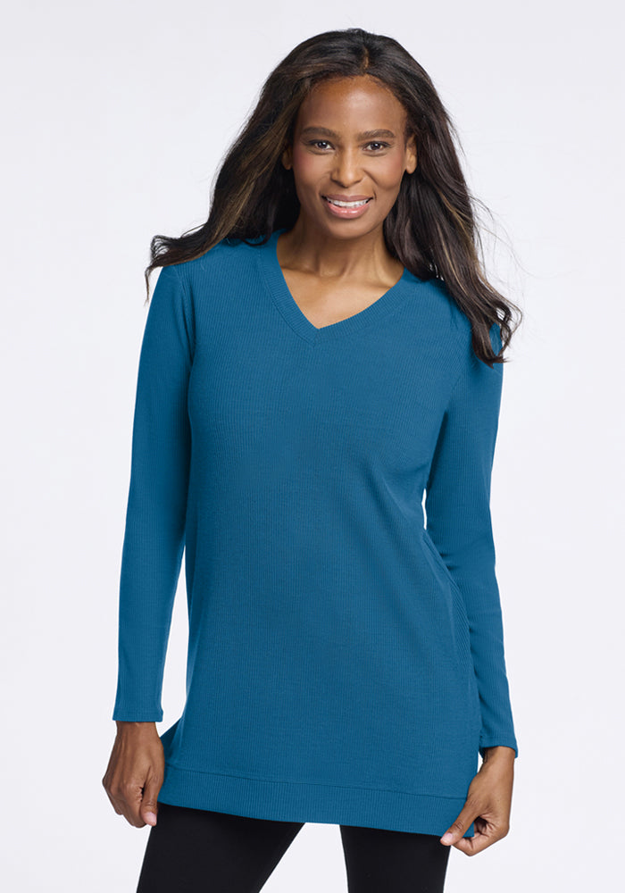 Woman in Woolx Evie Ribbed Tunic - Blue Pine and black leggings, smiling at the camera against a plain background. 