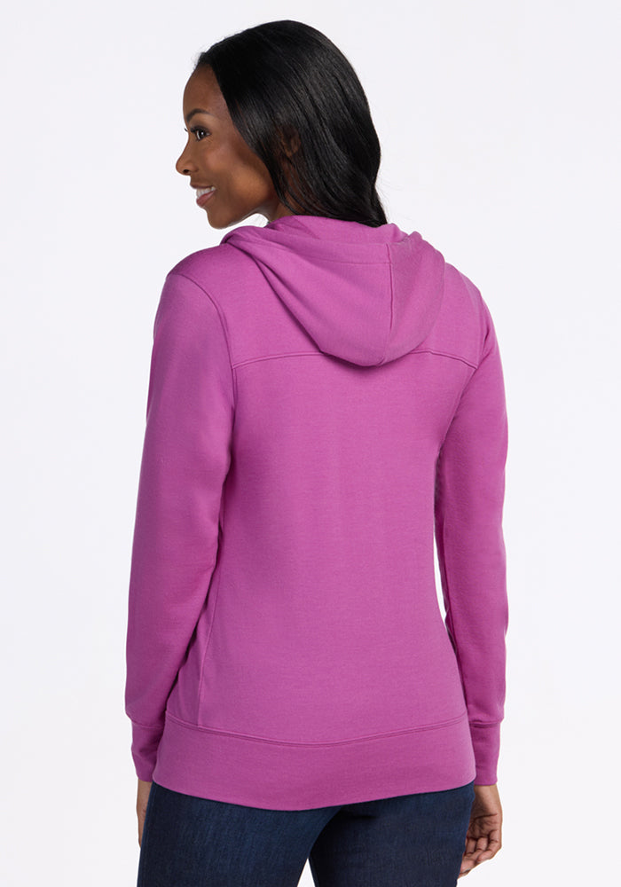 A woman faces away, smiling over her shoulder in the Woolx Ryann Hoodie - Purple Wine and dark jeans, set against a plain white background.