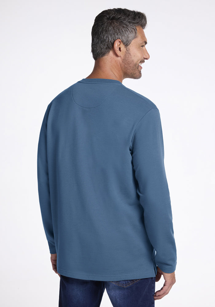 Man with short gray hair wears a Woolx Jackson Henley in Blue Ashes, shown from the back, smiling to the side.
