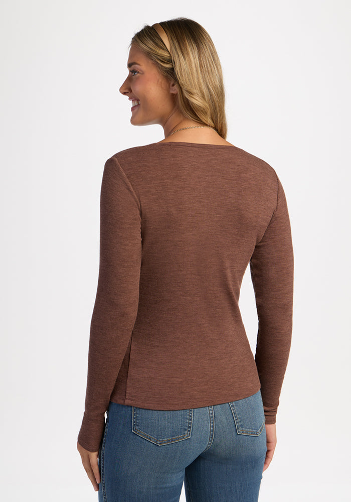 Woman in a Woolx Katie Ribbed Long Sleeve - Sable Heather and blue jeans stands smiling with her back to the camera.