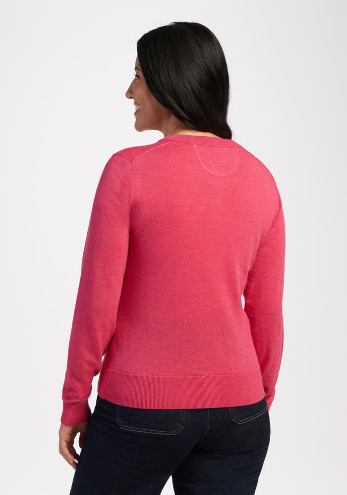 Woman with long dark hair in the Woolx Caitlin Sweater - Vivid Rose and jeans, smiling against a plain background.