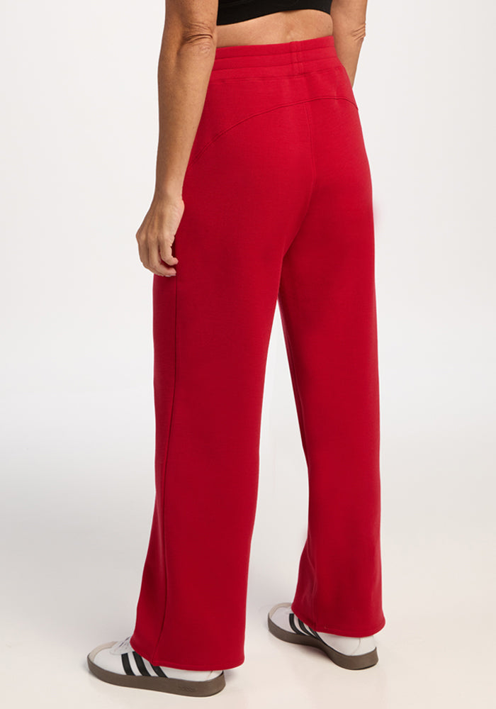 Person in Woolx Bree Lounge Pants - Maraschino Cherry, paired with white sneakers, stands against a plain background.