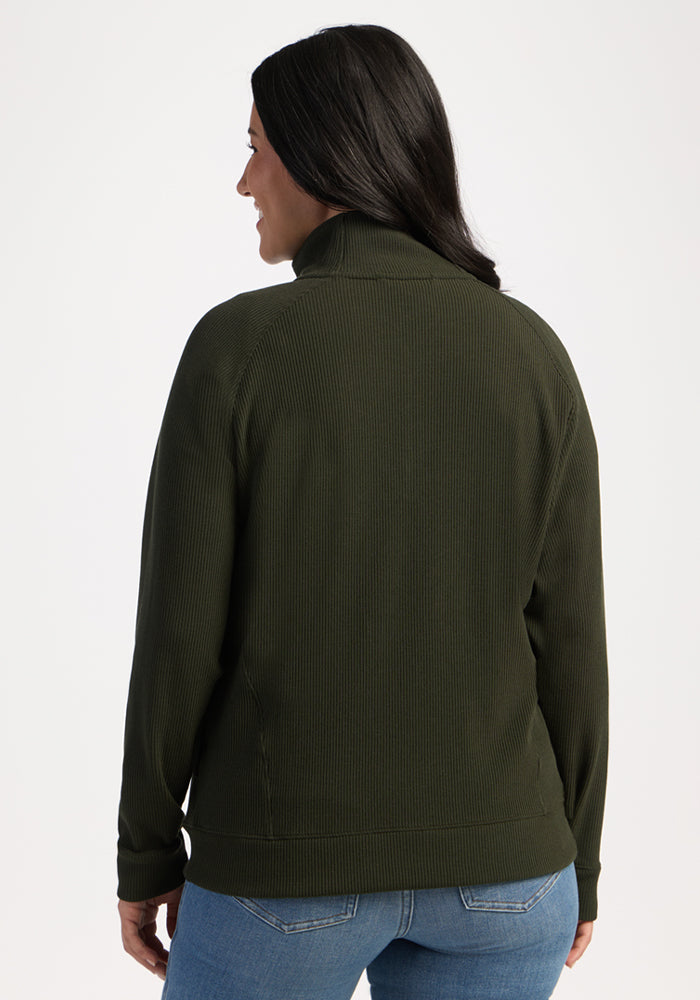 Woman in blue jeans and olive Quinn Ribbed 1/4 Zip by Woolx, long dark hair, seen from the back.