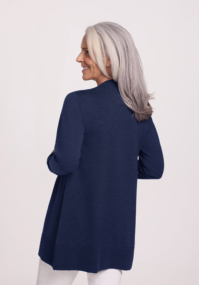 Woman with long gray hair in a Woolx Macie Sweater - Ocean Cavern, smiling and looking over her shoulder.