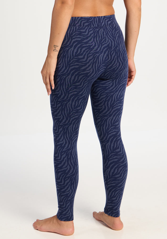 Person wears Woolx Taylor Baselayer Leggings in Midnight Safari, barefoot in a studio with a plain background.