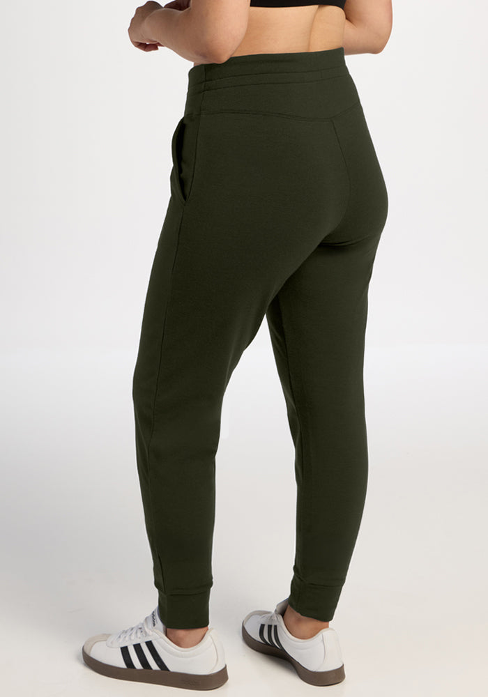 Person wears Woolx Willa Joggers in Duffel Bag and white sneakers, shown from the back on a plain light background.
