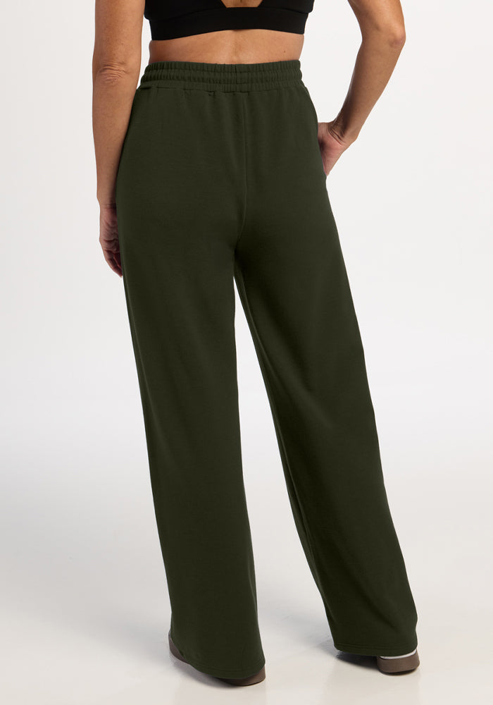 Person models Woolx Eloise Wide Leg Pants in Duffel Bag with a black top, back to camera, hand on hip.