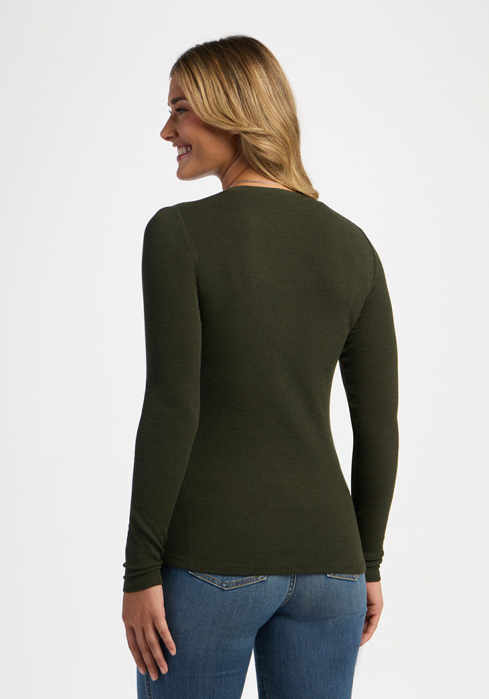 Woman in a Woolx Reese Ribbed Henley - Duffel Bag and blue jeans, smiling with her back to the camera.