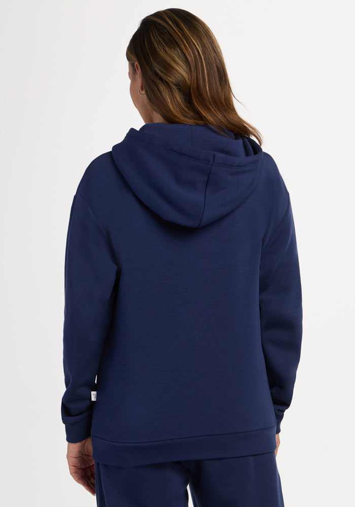 A person with brown hair wears a Woolx Avery Hoodie - Ocean Cavern and matching pants, facing away from the camera.