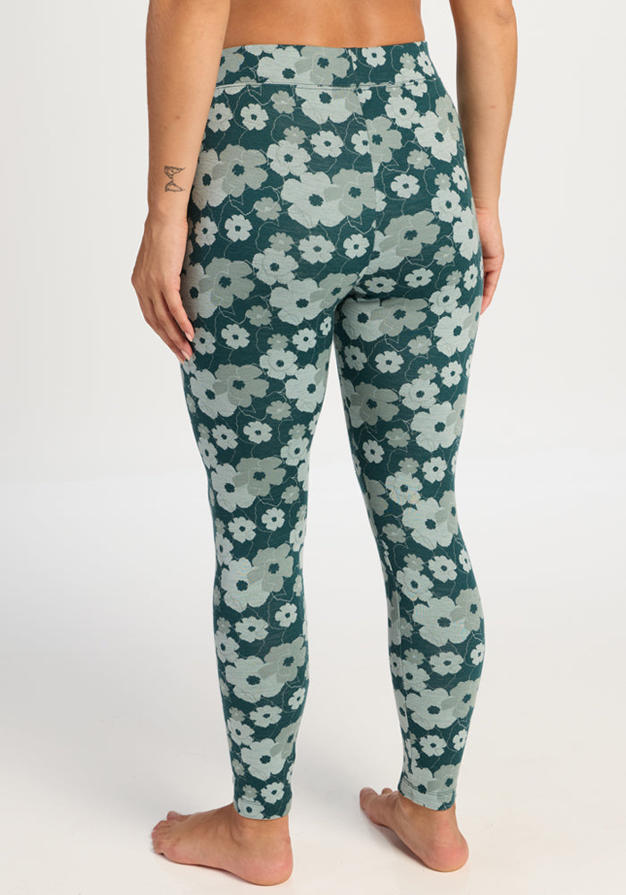 Barefoot person in Woolx Taylor Baselayer Leggings - Coastal Wildflower, facing away, small arm tattoo visible.