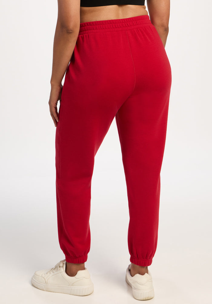 Model wears Woolx Parker Sweatpants in Maraschino Cherry, white sneakers, and a black top, seen from the back.