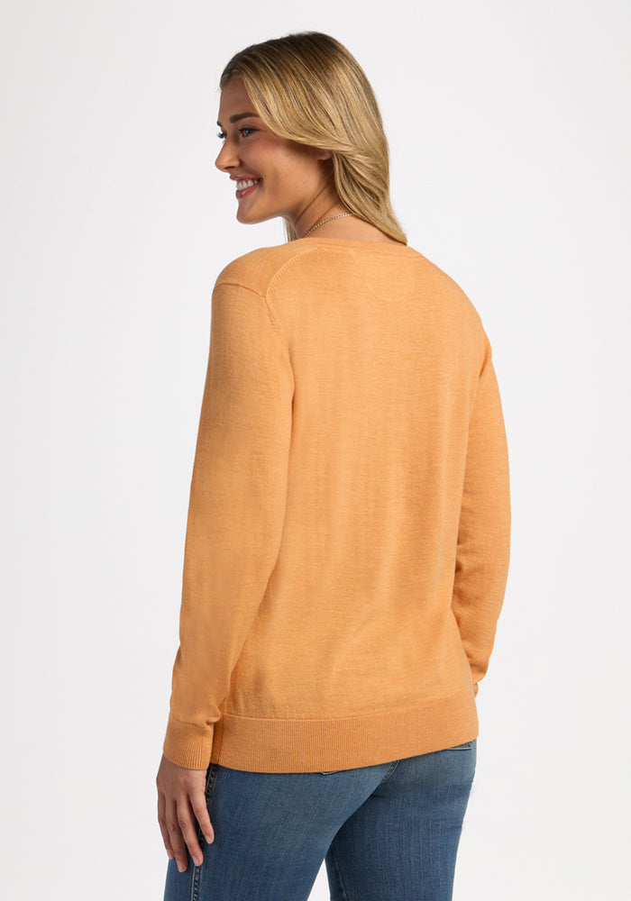 Woman in the Woolx Francesca Sweater - Butterscotch and blue jeans smiles, facing away from the camera.
