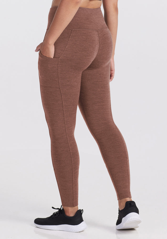 Model in Woolx Piper Pocket Petite - Sable Heather leggings and black sneakers, standing on a white background.