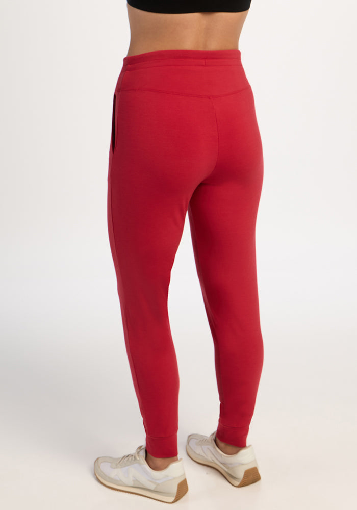 Person wearing Woolx Madden Joggers - Maraschino Cherry, white sneakers, black top, on a white background.