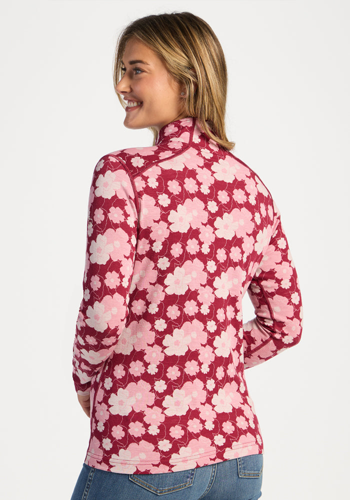 Woman smiles, facing away, in Woolx Emi 1/4 Zip - Floral Crush Merino wool top and blue jeans.