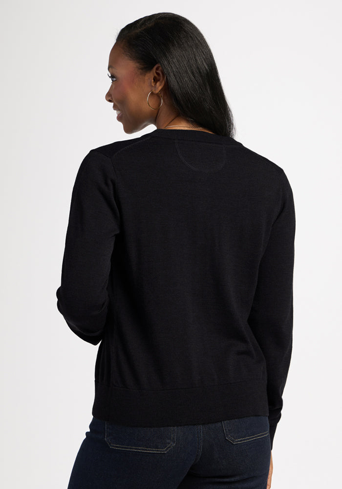 Woman with long dark hair in the Woolx Caitlin Sweater - Black and jeans, shown from the back, looking over shoulder.