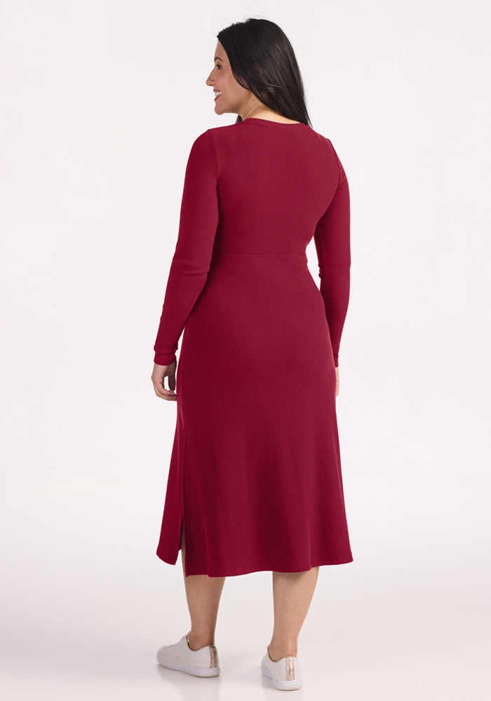 Woman in a Woolx Caroline Ribbed Twirl Dress - Beet Red and white sneakers, standing with her back to us.