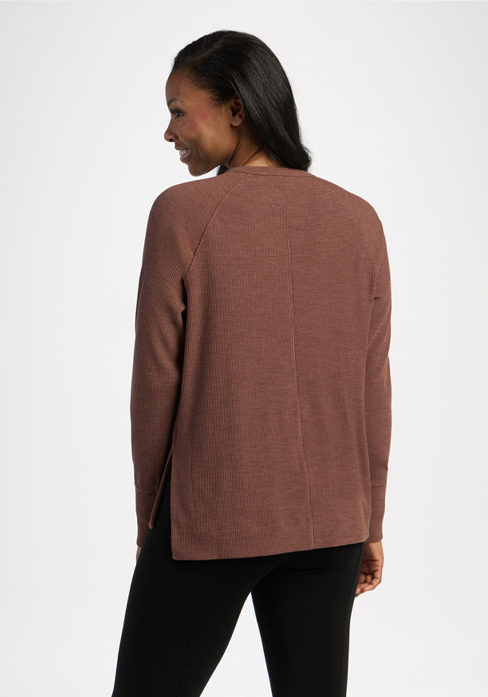 Woman in a Woolx Ainsley Sweater - Sable Heather and black pants, facing away from the camera, smiling.