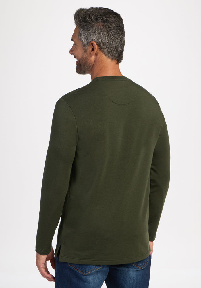 Gray-haired man wears Woolx Jackson Henley in Duffel Bag green and blue jeans, back turned to the camera.