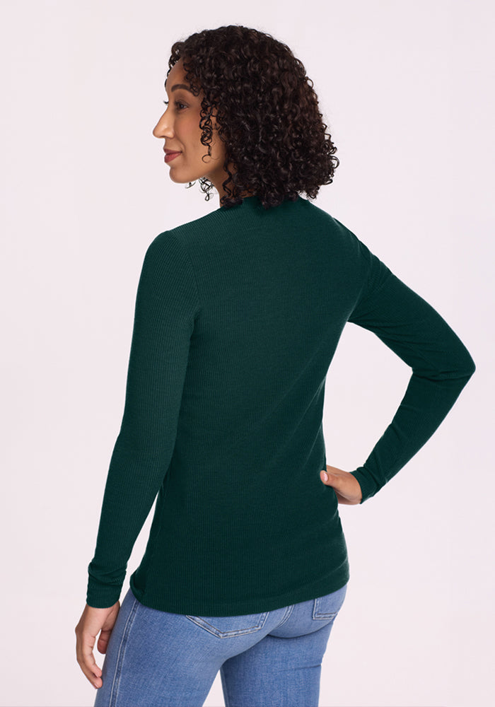 Woman with curly hair wears the Woolx Hadley Ribbed Crew in Deep Pine and jeans, facing away from the camera.