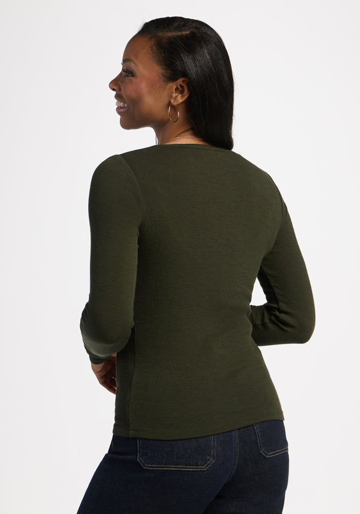 Woman in Woolx Katie Ribbed Long Sleeve - Duffel Bag and jeans, smiling, facing away, on plain white background.