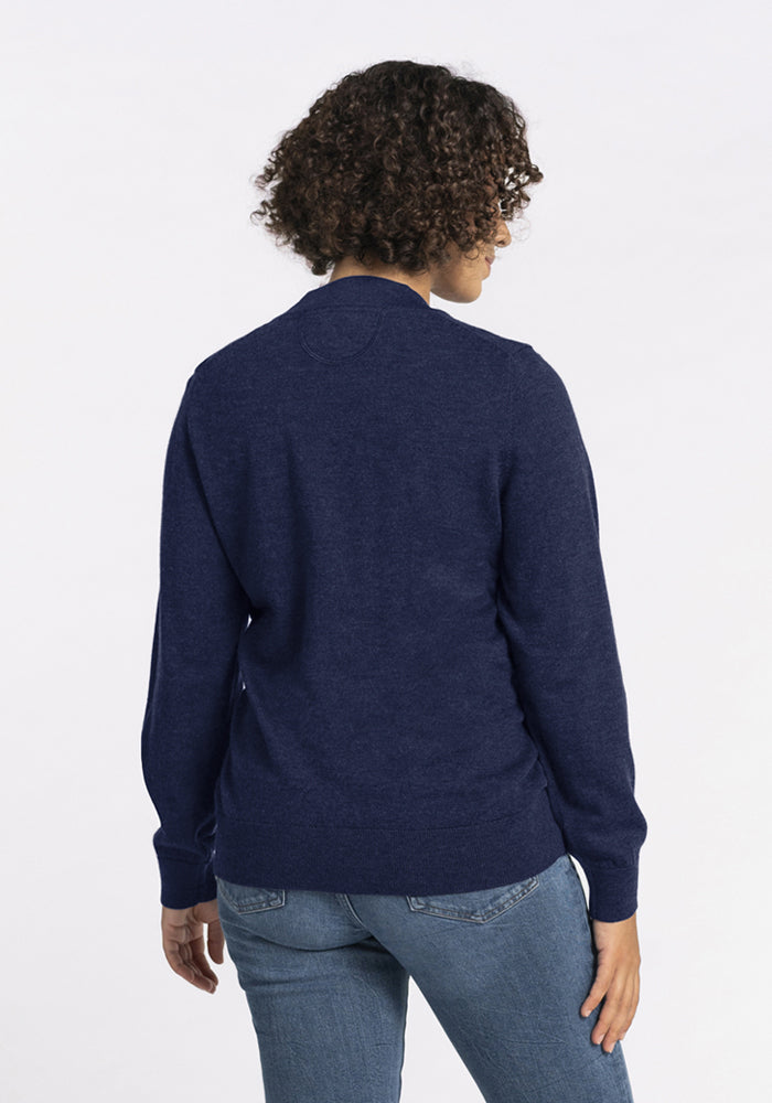 Person with short curly hair in a Woolx Gia Sweater - Ocean Cavern and jeans, back facing the camera.