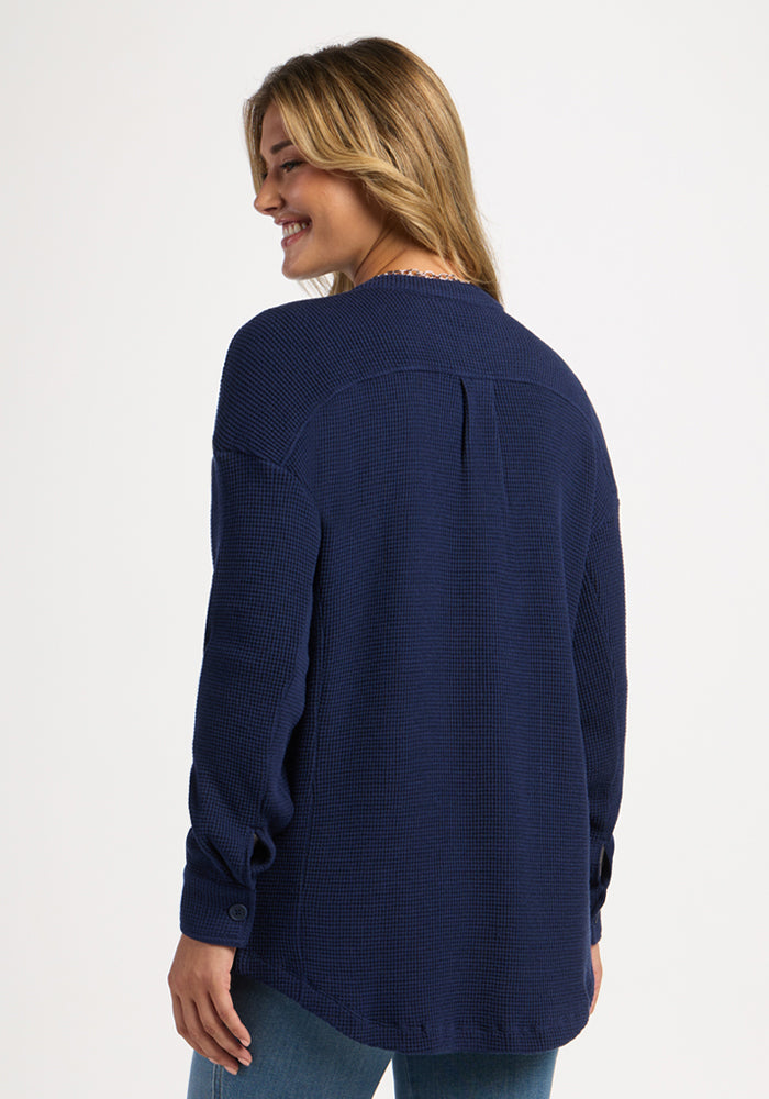Woman smiles in a Woolx Oaklynn Waffle Shacket - Ocean Cavern, facing away from the camera against a plain background.