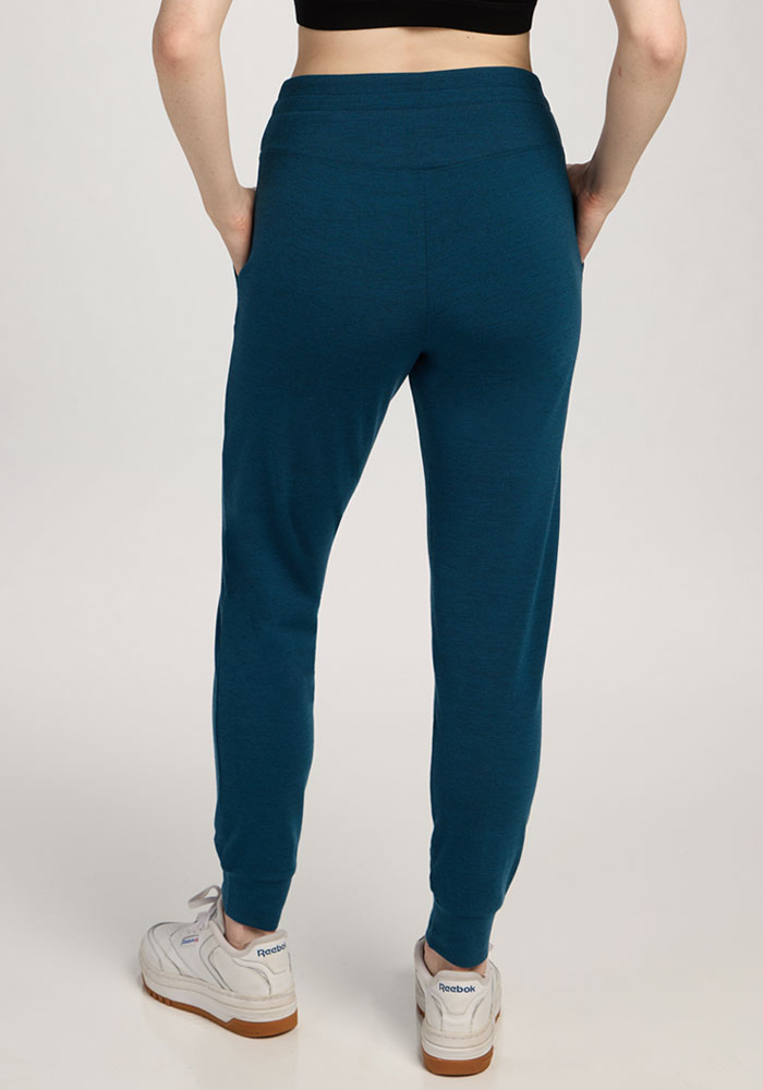 Person wearing Woolx Madden Petite Joggers in Majolica Blue, white sneakers, and a black crop top from the back.