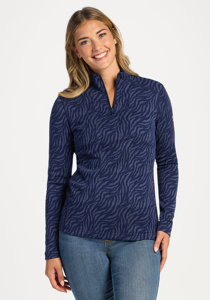 Smiling woman in Woolx Emi 1/4 Zip - Midnight Safari pullover and jeans, against a plain white background. 