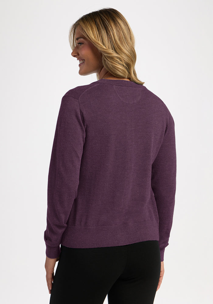 Woman with blonde hair models the Woolx Caitlin Sweater in Purple Iris, smiling over her shoulder.