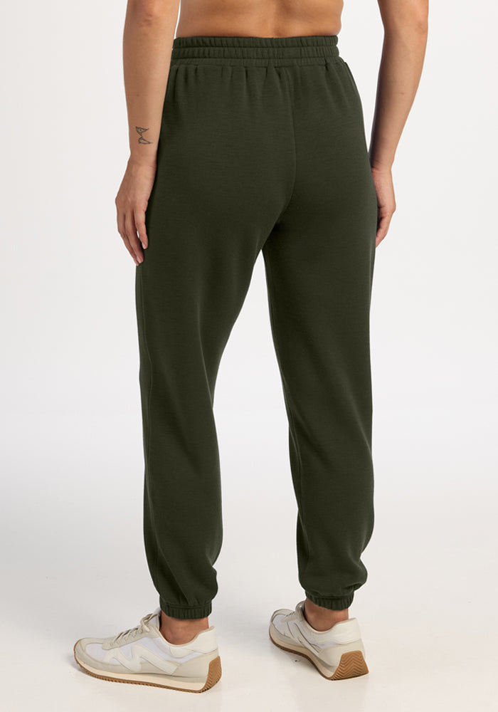 Model wears Woolx Parker Sweatpants in Duffel Bag and white sneakers, back to camera, plain background.