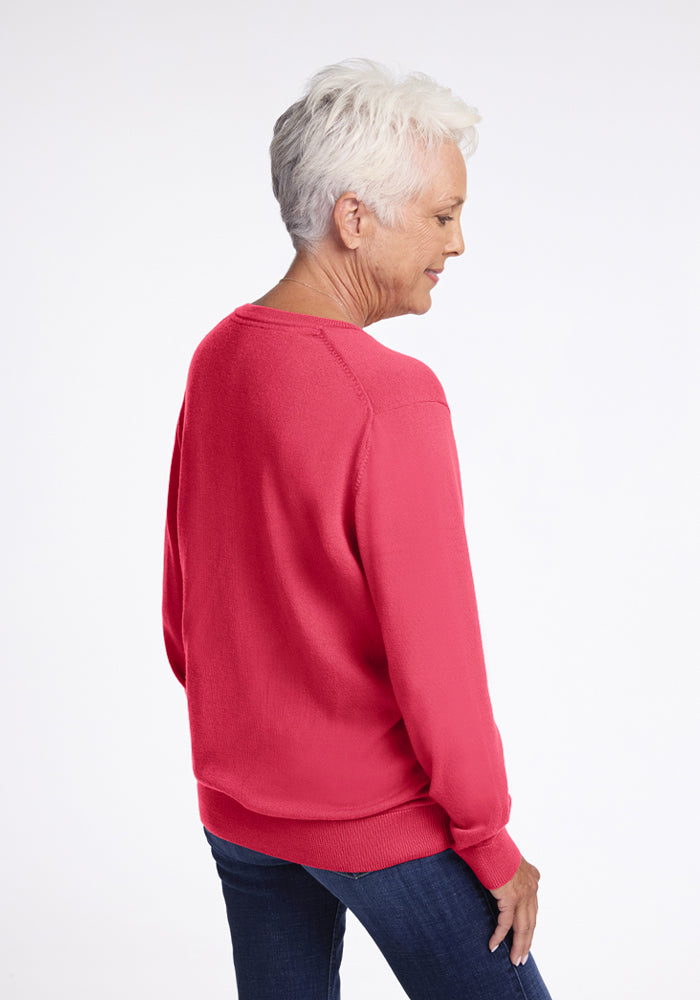 Older woman in Woolx Francesca Sweater - Vivid Rose, with blue jeans, facing away against a white background.