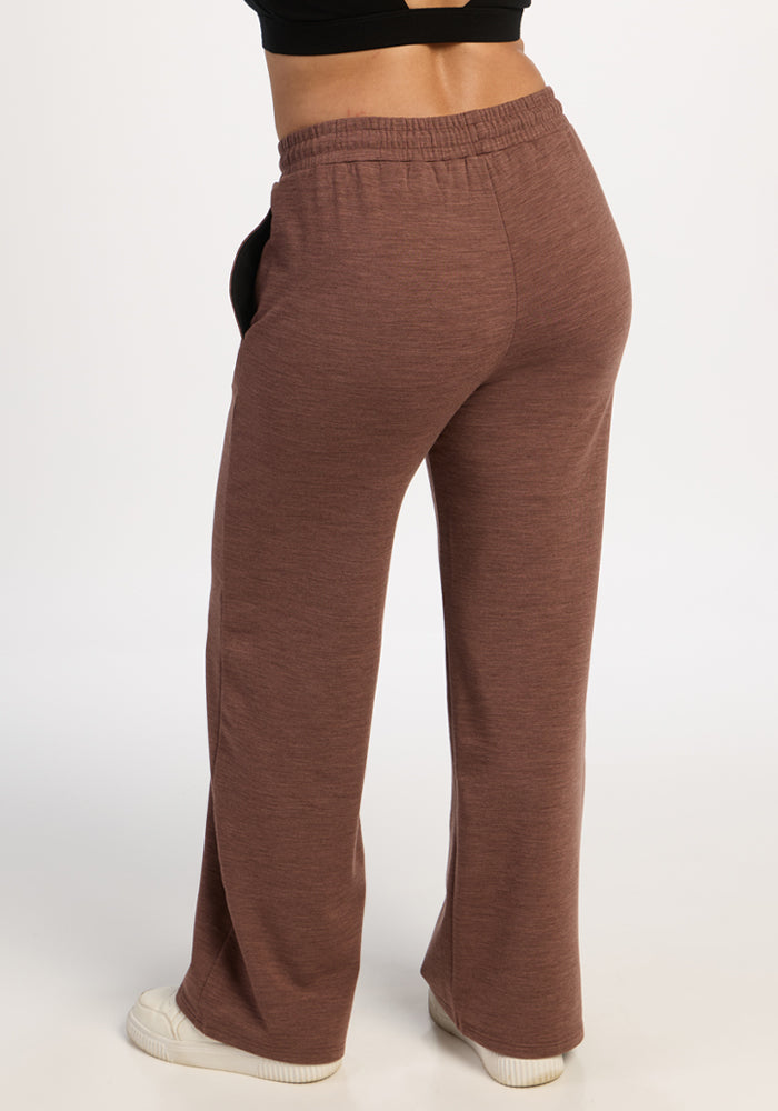 Model in Woolx Eloise Wide Leg Pants - Sable Heather, white sneakers, and black crop top against a plain background.