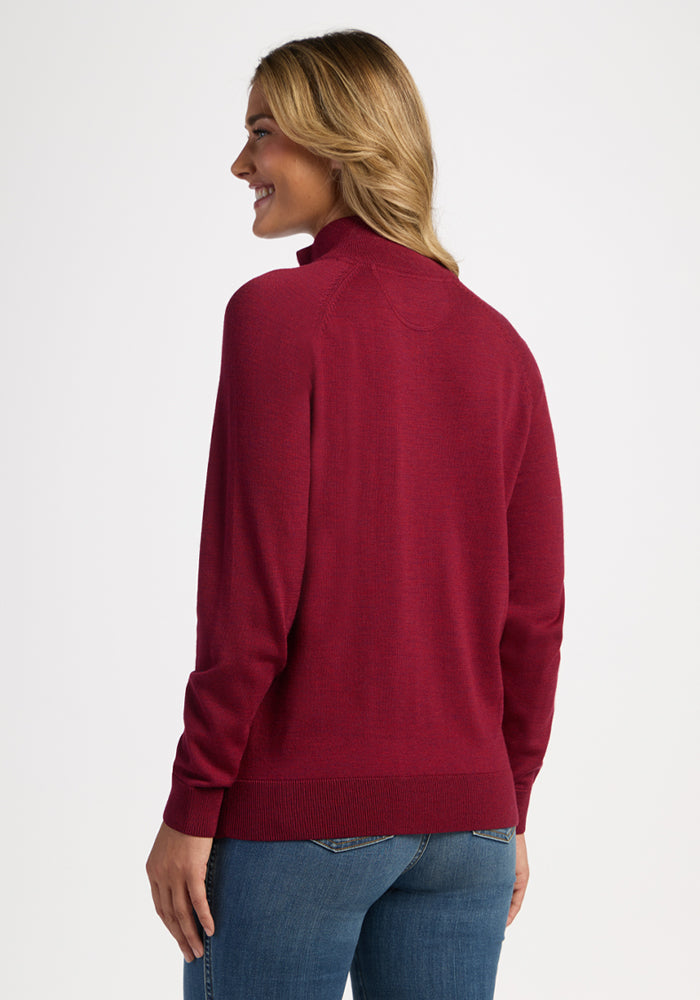 Smiling woman in Woolx Collins Half Zip Sweater - Beet Red and jeans, facing away against a plain background.