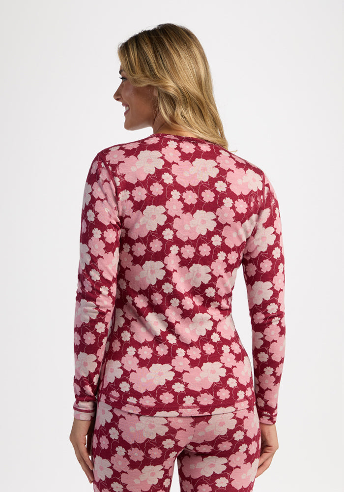 Woman faces away in Woolx Maddie Baselayer Top - Floral Crush, pink and burgundy, against a white background.
