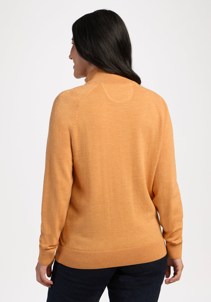 Woman wears the Woolx Collins Half Zip Sweater in Butterscotch, standing with her back to the camera.