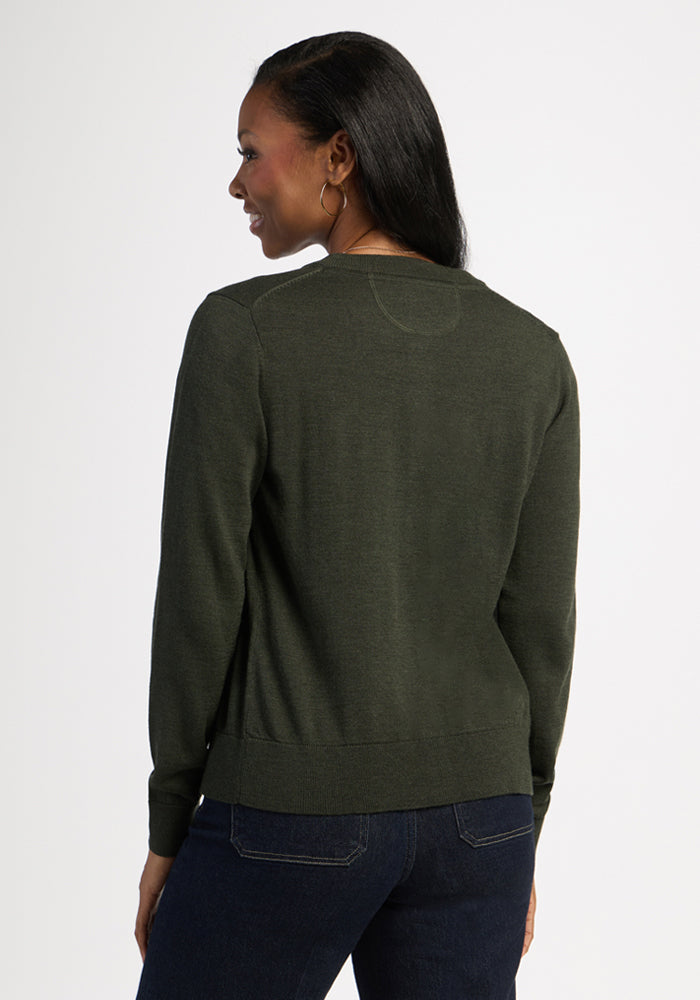 Woman wearing Woolx Caitlin Sweater in Duffel Bag and blue jeans stands facing away against a white background.