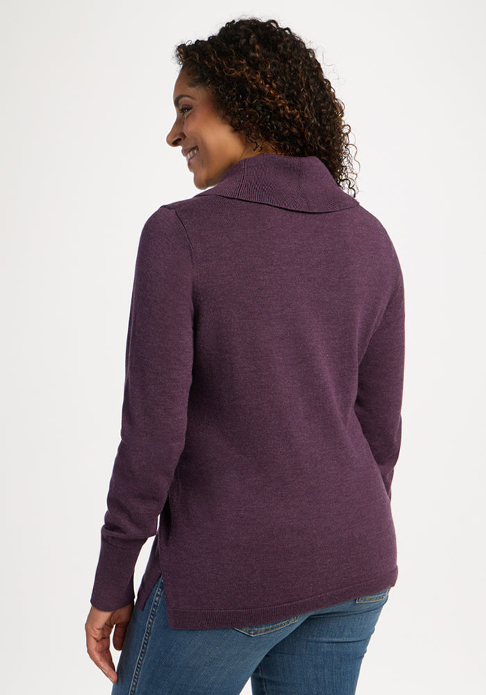 Woman smiles in Woolx Josie Cowl Neck Sweater - Purple Iris with blue jeans, facing away on white background.