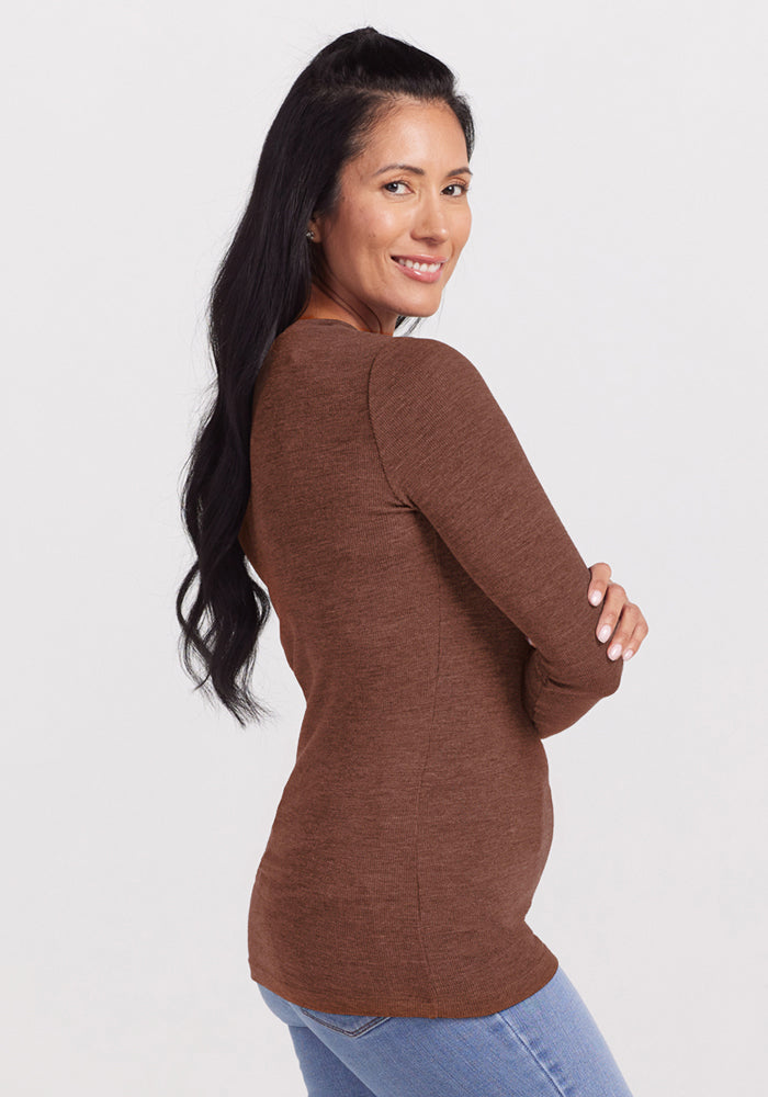 Woman with long dark hair in Woolx Reese Ribbed Henley - Sable Heather and blue jeans, smiling sideways.