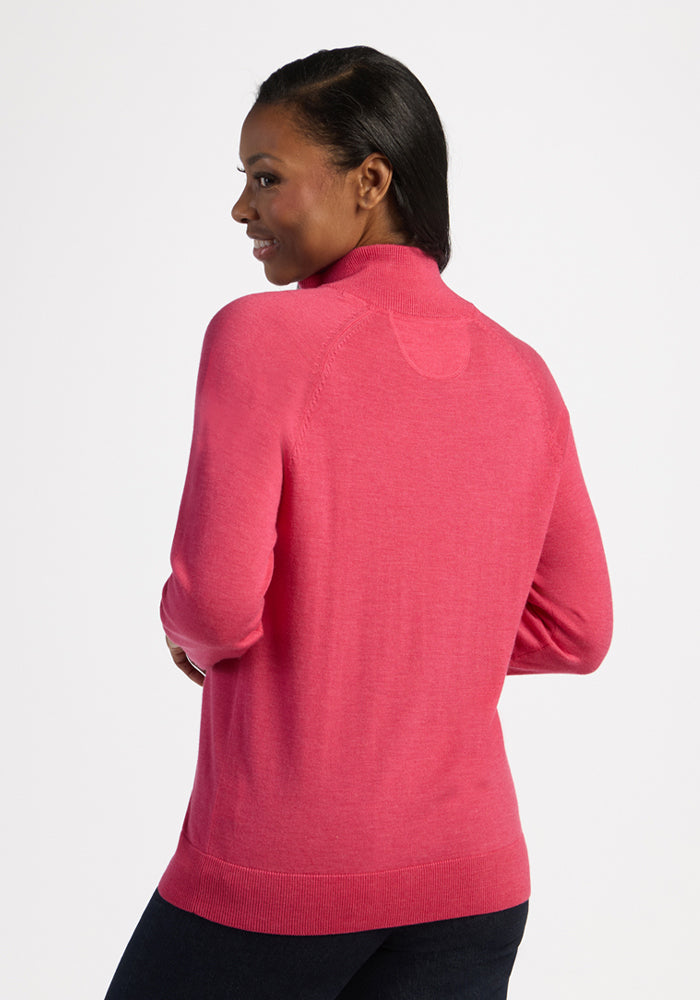 Woman in a Woolx Collins Half Zip Sweater in Vivid Rose, facing away and smiling against a white background.